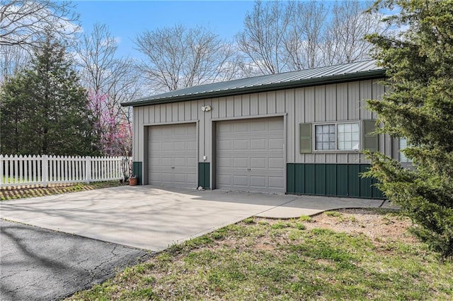 garage featuring concrete driveway and fence