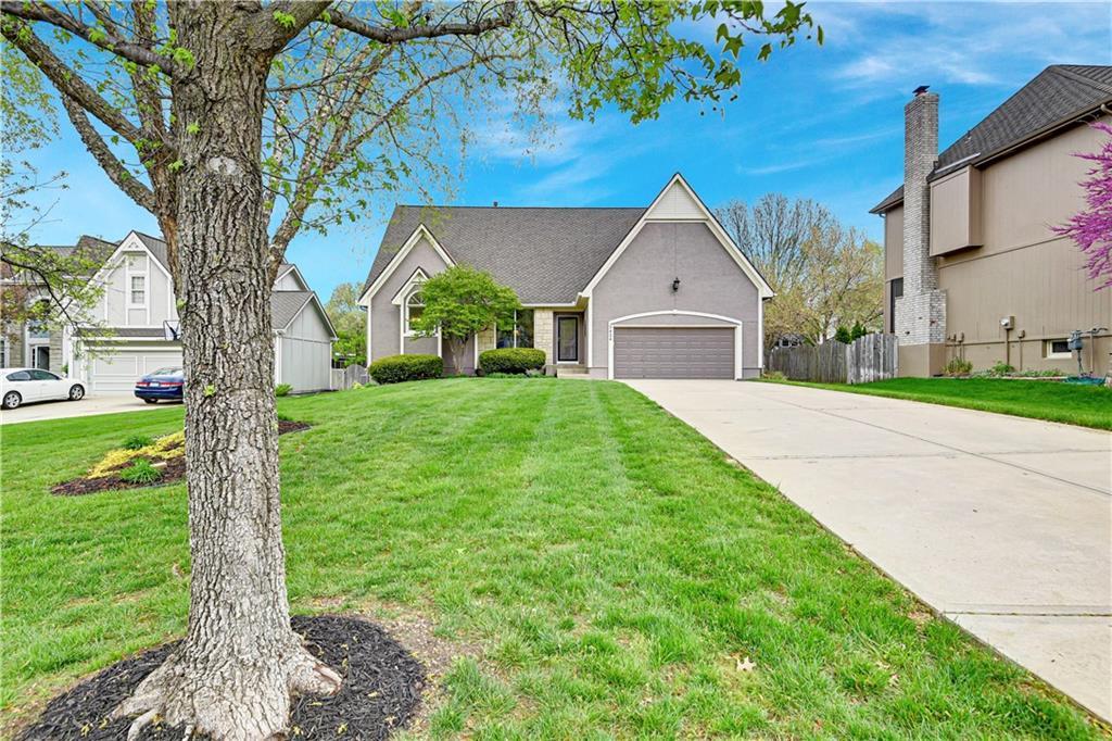 traditional-style home featuring a garage, concrete driveway, a front yard, and fence