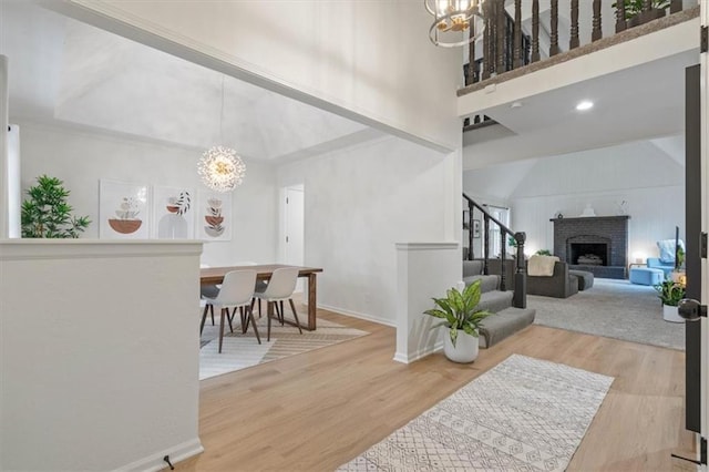 interior space featuring an inviting chandelier, stairs, wood finished floors, a fireplace, and high vaulted ceiling