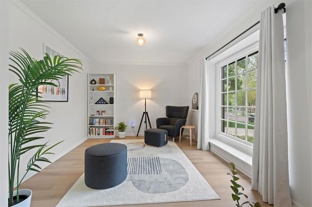 living area with crown molding and light wood-style flooring