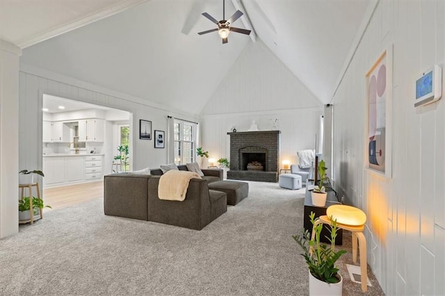 living area featuring vaulted ceiling, light carpet, a ceiling fan, and a brick fireplace