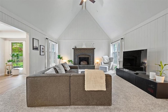 living area featuring a brick fireplace, carpet flooring, ceiling fan, and lofted ceiling