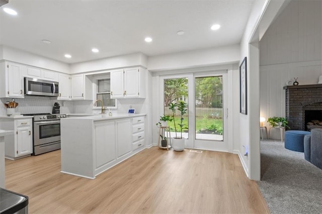 kitchen featuring light countertops, light wood finished floors, appliances with stainless steel finishes, and white cabinets