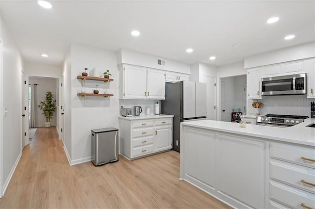 kitchen with white cabinets, stainless steel appliances, recessed lighting, decorative backsplash, and light wood-type flooring