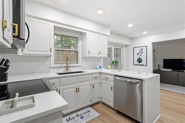 kitchen featuring a sink, light countertops, light wood-style flooring, stainless steel appliances, and decorative backsplash