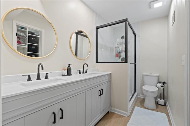 bathroom featuring a sink, wood finished floors, toilet, and a shower stall