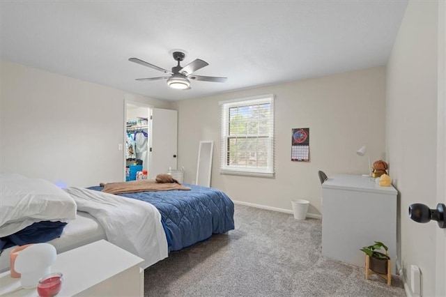bedroom with light colored carpet, baseboards, ceiling fan, and a spacious closet
