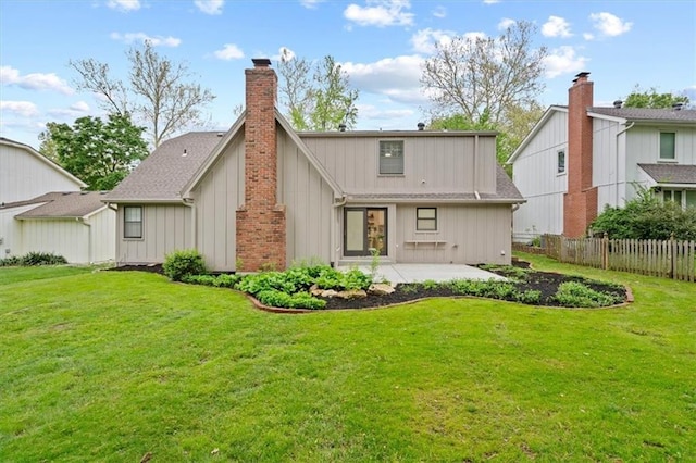 rear view of property with fence, a chimney, a yard, and a patio area