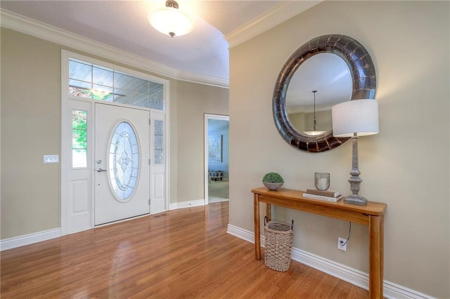 foyer featuring baseboards, ornamental molding, and wood finished floors