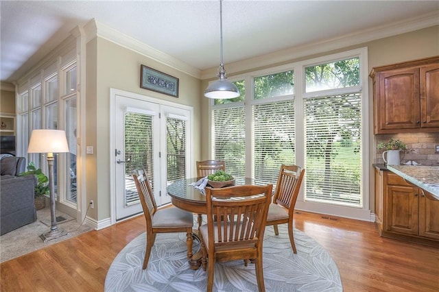 dining room featuring crown molding, baseboards, visible vents, and light wood-type flooring