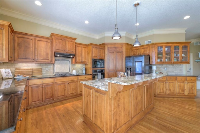 kitchen with glass insert cabinets, brown cabinetry, black appliances, and under cabinet range hood