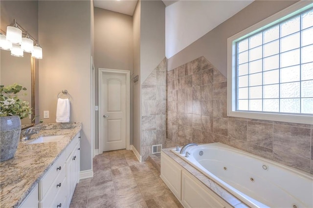 full bathroom with baseboards, visible vents, a tub with jets, and vanity