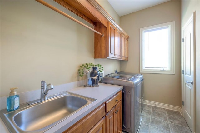 laundry room with separate washer and dryer, a sink, cabinet space, and baseboards