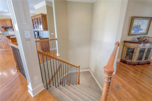 stairs with baseboards, ornamental molding, and wood finished floors