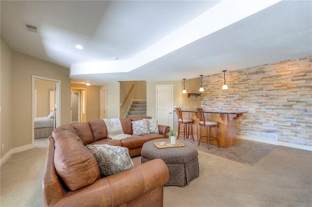 living area with visible vents, carpet, stairs, and bar