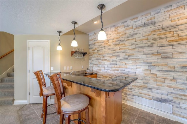 bar with a textured ceiling, wet bar, dark tile patterned flooring, and stairway