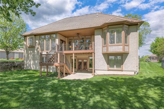 back of property featuring stairs, ceiling fan, stucco siding, and a yard