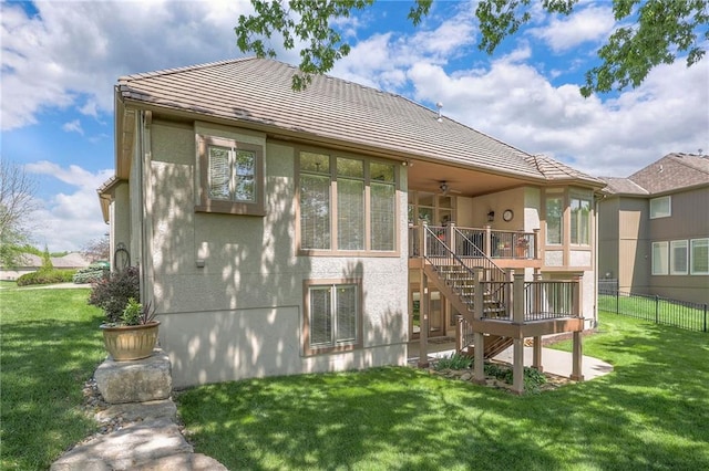 back of house with fence, stairs, stucco siding, a lawn, and a ceiling fan