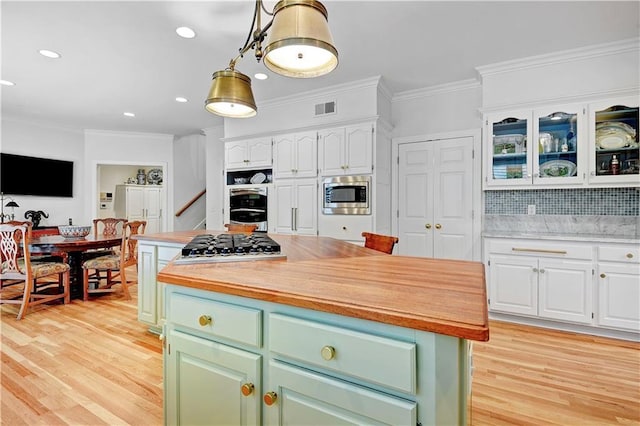 11405 Manor St, Leawood, KS 66211 - kitchen featuring stainless steel microwave, white cabinetry, light wood finished floors, light countertops, and crown molding