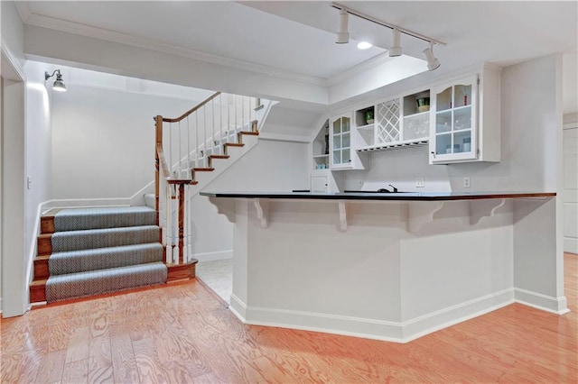 11405 Manor St, Leawood, KS 66211 - kitchen with rail lighting, open shelves, light wood-style floors, crown molding, and a kitchen bar