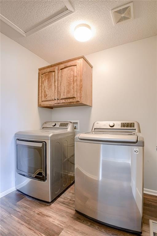 496 S 137th St, Bonner Springs, KS 66012 - laundry room with washer and clothes dryer, cabinet space, light wood finished floors, a textured ceiling, and baseboards