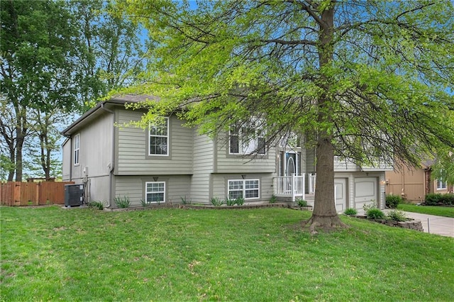 view of front facade featuring central AC unit, fence, driveway, and a front yard