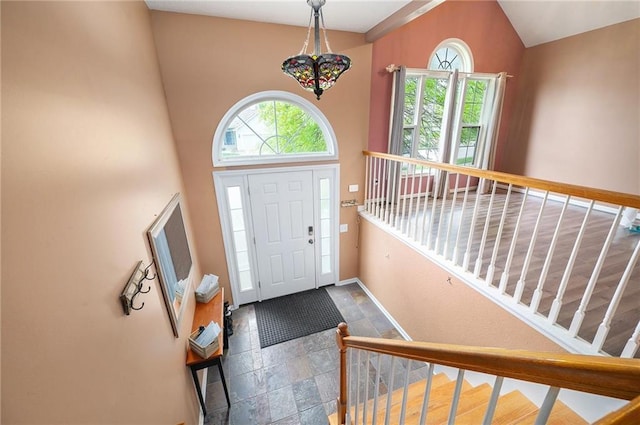 foyer featuring stone tile flooring, baseboards, and stairway