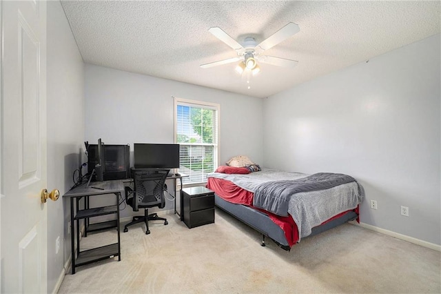 bedroom featuring a ceiling fan, a textured ceiling, light colored carpet, and baseboards