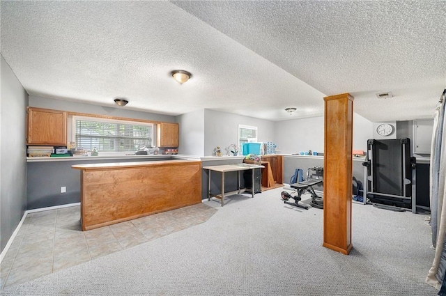 kitchen featuring visible vents, a textured ceiling, brown cabinets, and a healthy amount of sunlight