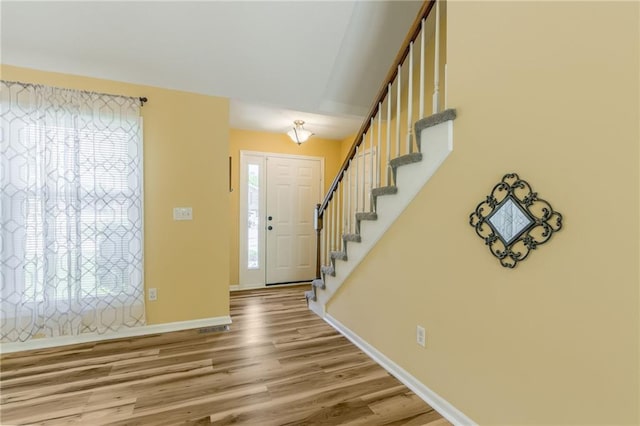 entrance foyer with baseboards, wood finished floors, and stairway