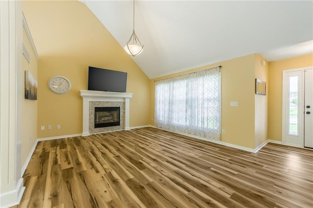 unfurnished living room with baseboards, a tile fireplace, wood finished floors, and lofted ceiling