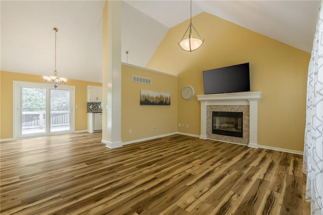 unfurnished living room with visible vents, wood finished floors, a chandelier, and a tiled fireplace
