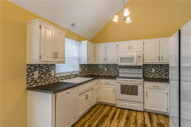 kitchen with a sink, dark countertops, lofted ceiling, and white appliances