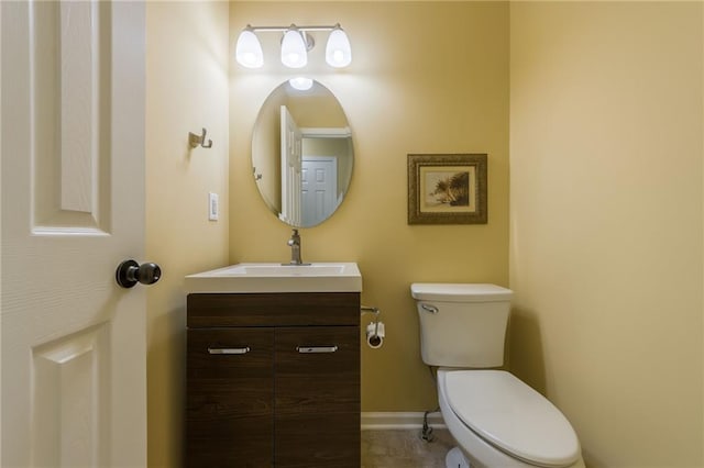 half bathroom with vanity, baseboards, and toilet