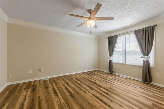 empty room featuring crown molding, a textured ceiling, a ceiling fan, wood finished floors, and visible vents
