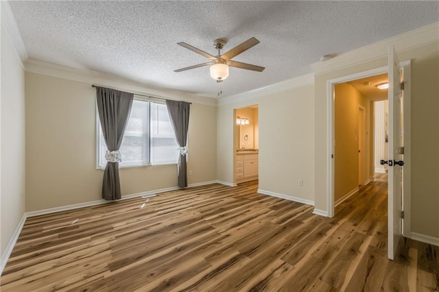 empty room featuring crown molding, a textured ceiling, a ceiling fan, baseboards, and wood finished floors
