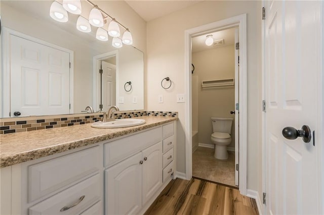 full bath with vanity, decorative backsplash, wood finished floors, toilet, and baseboards