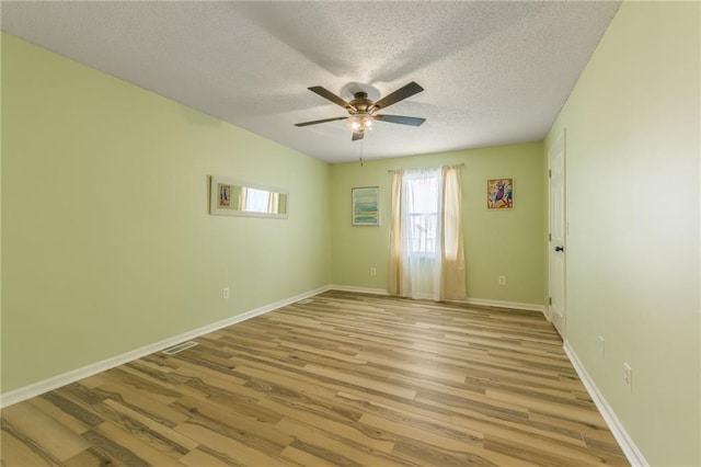 empty room with baseboards, a ceiling fan, a textured ceiling, and wood finished floors