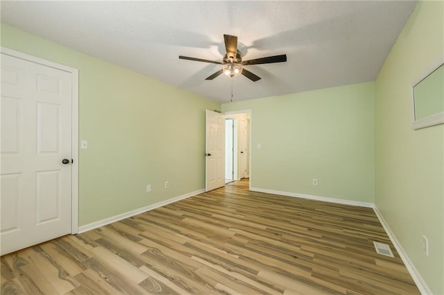 unfurnished bedroom featuring a textured ceiling, baseboards, a ceiling fan, and wood finished floors