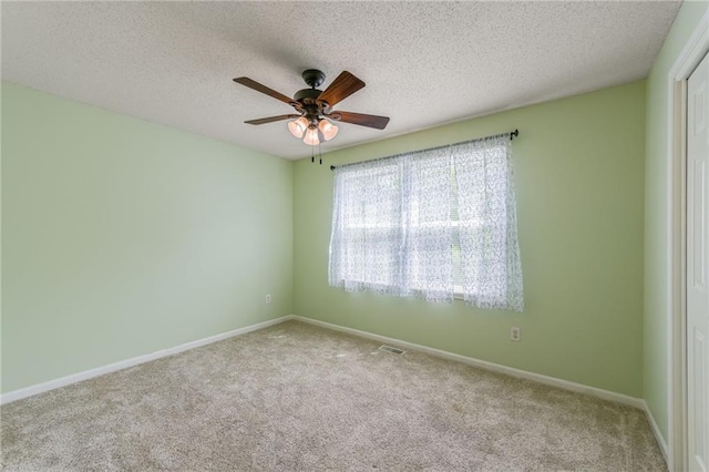 carpeted spare room featuring baseboards, ceiling fan, and a textured ceiling