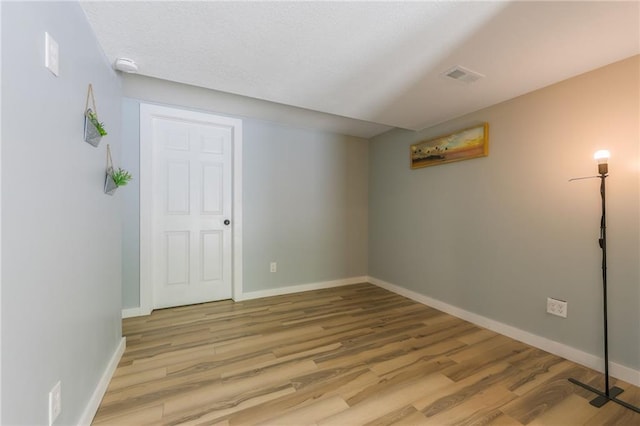unfurnished room featuring visible vents, baseboards, and wood finished floors