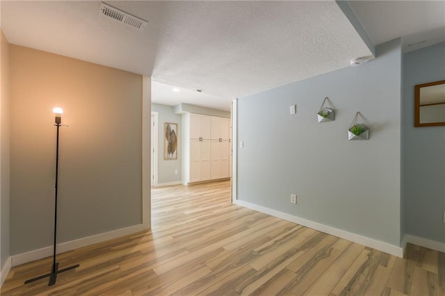 empty room with visible vents, baseboards, and light wood-type flooring