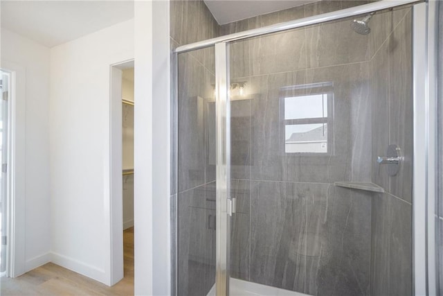 3806-3808 NW 93rd St, Kansas City, MO 64132 - bathroom featuring a shower stall, wood finished floors, a walk in closet, and baseboards