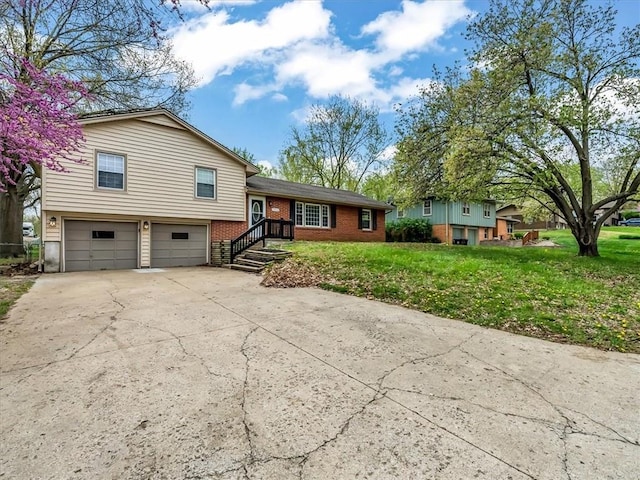 tri-level home featuring an attached garage, a front lawn, driveway, and brick siding