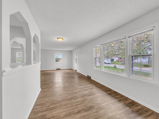 empty room featuring wood finished floors, baseboards, and a textured ceiling