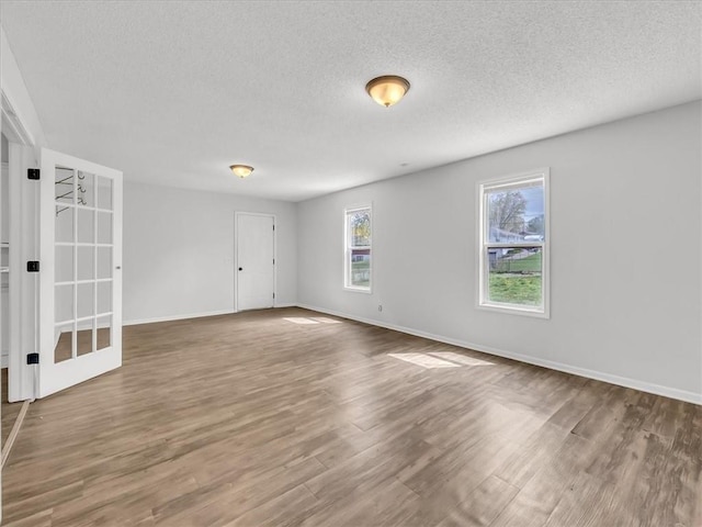 empty room featuring wood finished floors, a textured ceiling, and baseboards