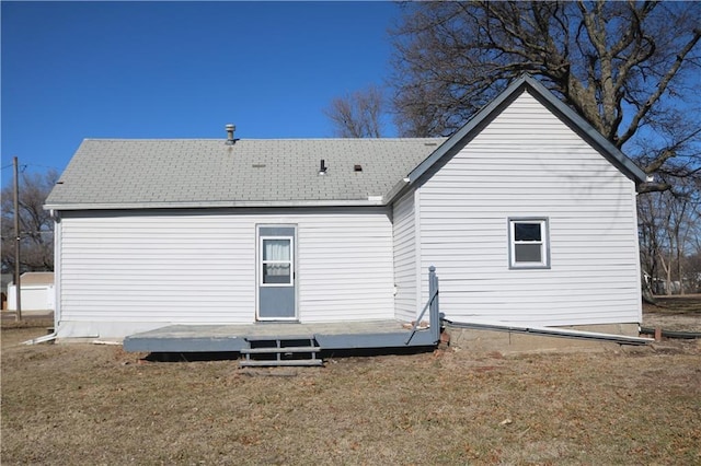 rear view of house featuring a lawn and roof with shingles