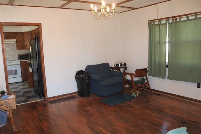 living area featuring dark wood-type flooring, baseboards, and a notable chandelier