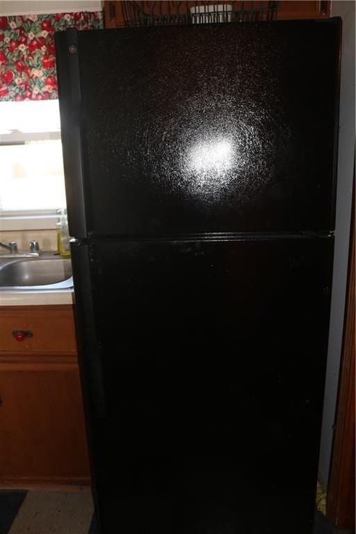 interior details with a sink, light countertops, and freestanding refrigerator