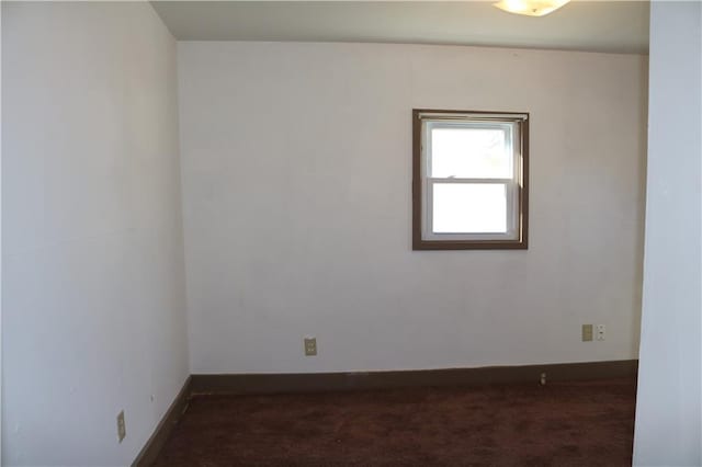 unfurnished room featuring dark carpet and baseboards